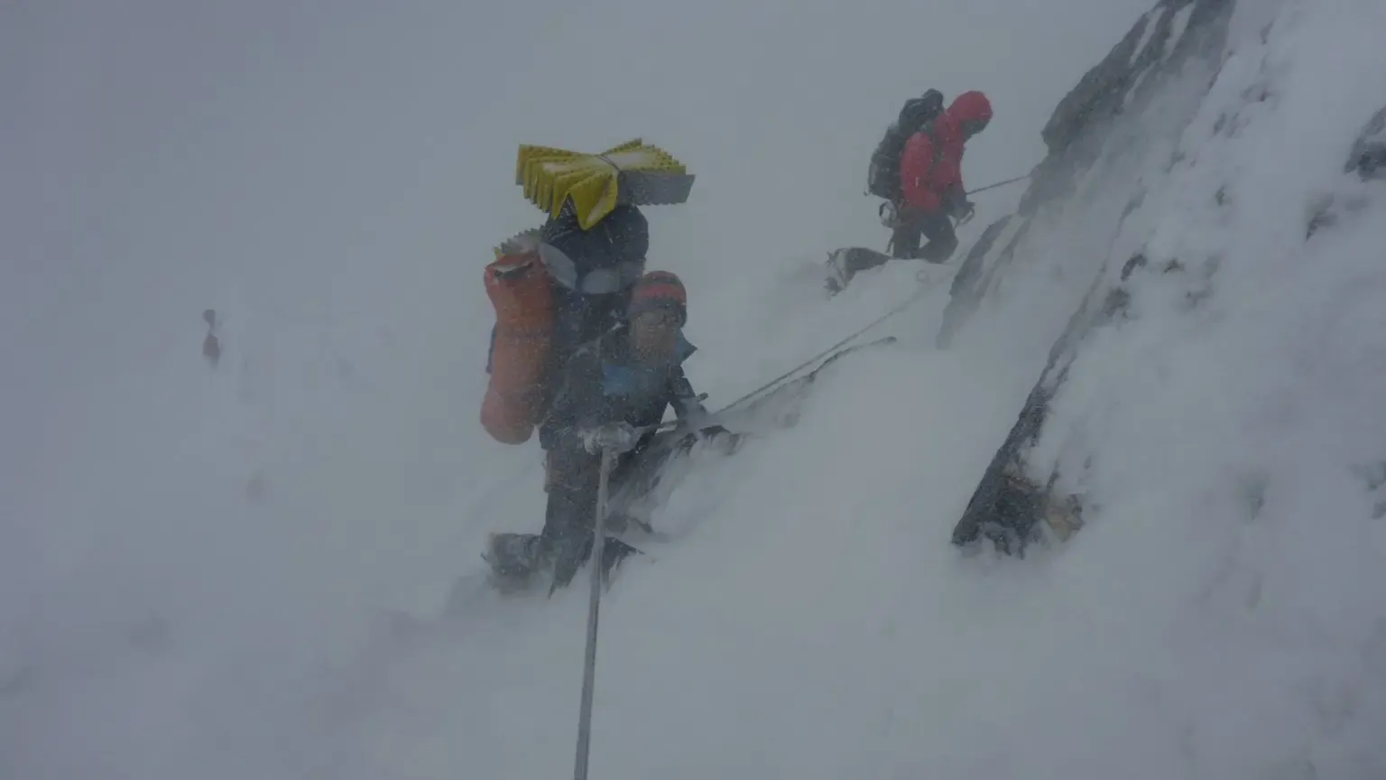 Am Fixseil im Schneesturm: zwei Bergsteiger sichern sich in der steilen Flanke